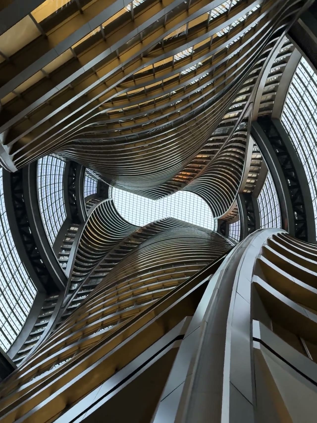 Curved modern architecture rising through a glass-roofed atrium